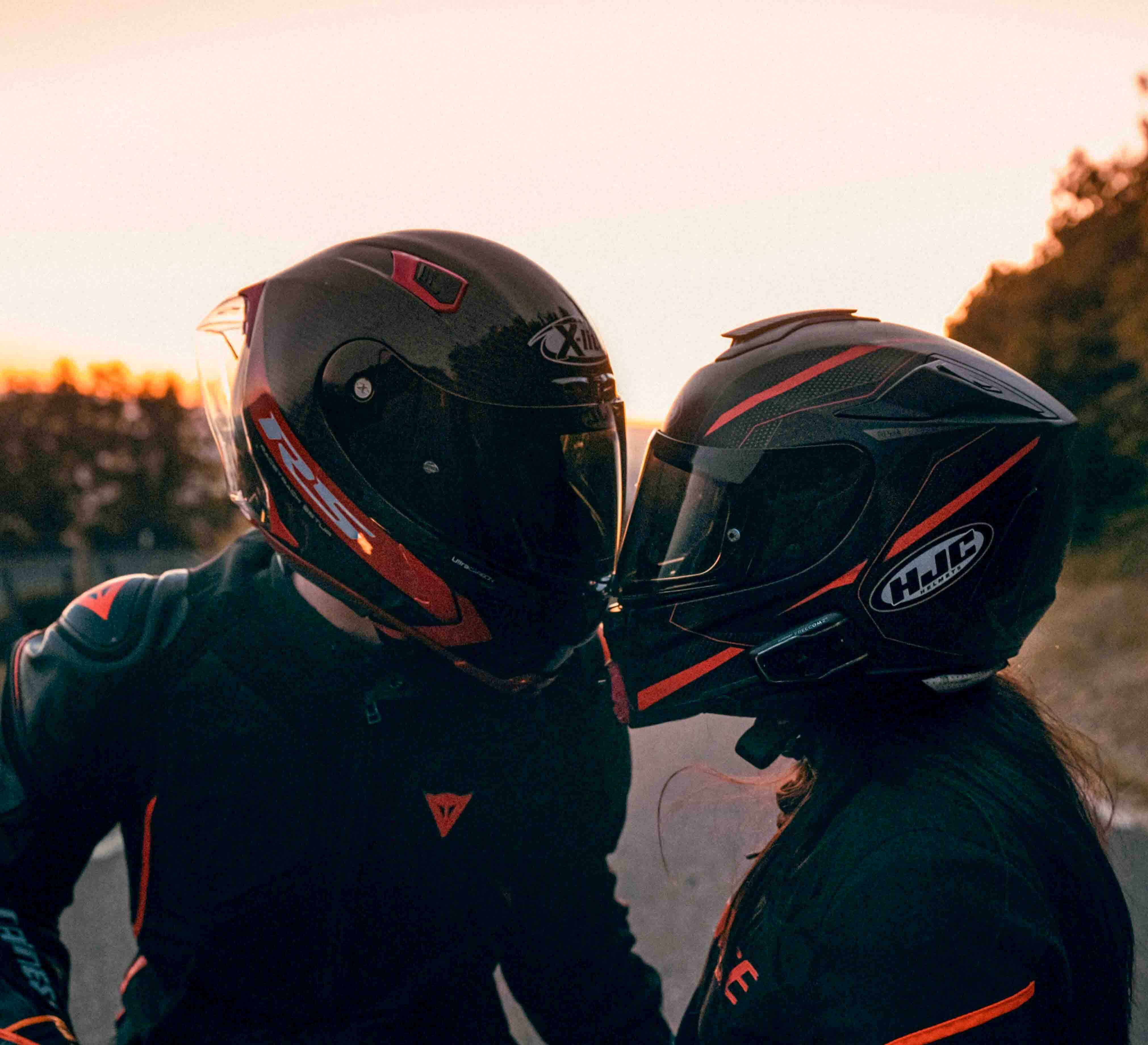 Two people in motorcycle helmets hugging.